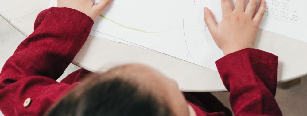 A child's drawing with crayons and other art supplies next to the drawing.