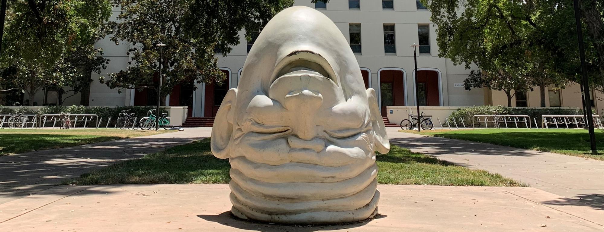 Eye on Mrak (Fatal Laff) — The upside-down head points away from the administration building, laughing. On the back of the head, a single eye stares at Mrak Hall.