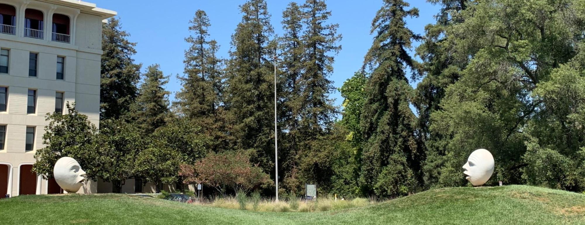 Hear No Evil, See No Evil: Two UC Davis Eggheads — Two Eggheads face each other on adjacent grassy knolls speaking out of the corners of their mouths, but both lack ears.