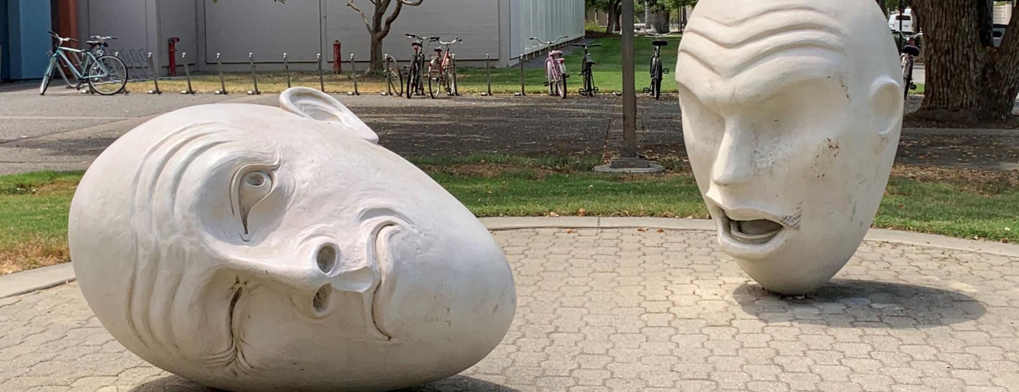 Yin & Yang: Two UC Davis Eggheads — one, with eyes closed, is speaking. The other head is lying on its ear with the back of its head facing the speaker.